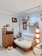 Clérachic teak floor lamp lit beside a white sofa, a vintage record player, and wooden dresser drawers in a retro-styled room.