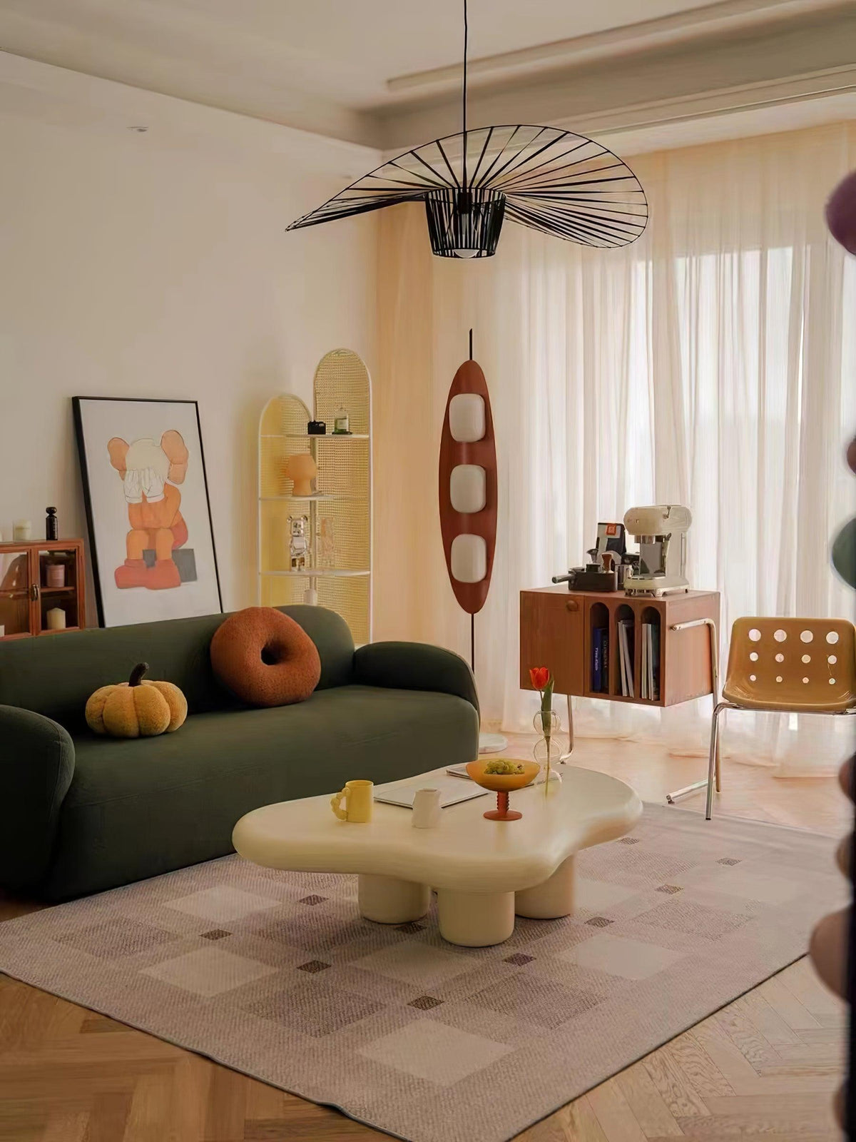 Clérachic teak floor lamp beside a green sofa and a cream coffee table, on parquet flooring beneath a woven pendant light.