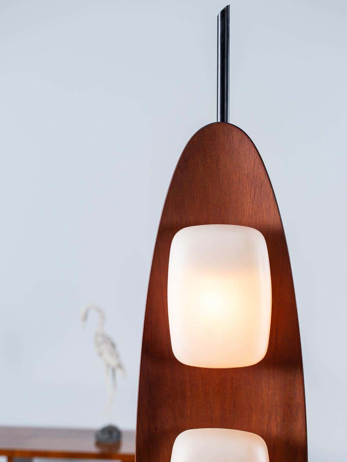 Close-up of a Clérachic teak floor lamp's tapered top and uppermost glass shade, showing the wood grain in detail.