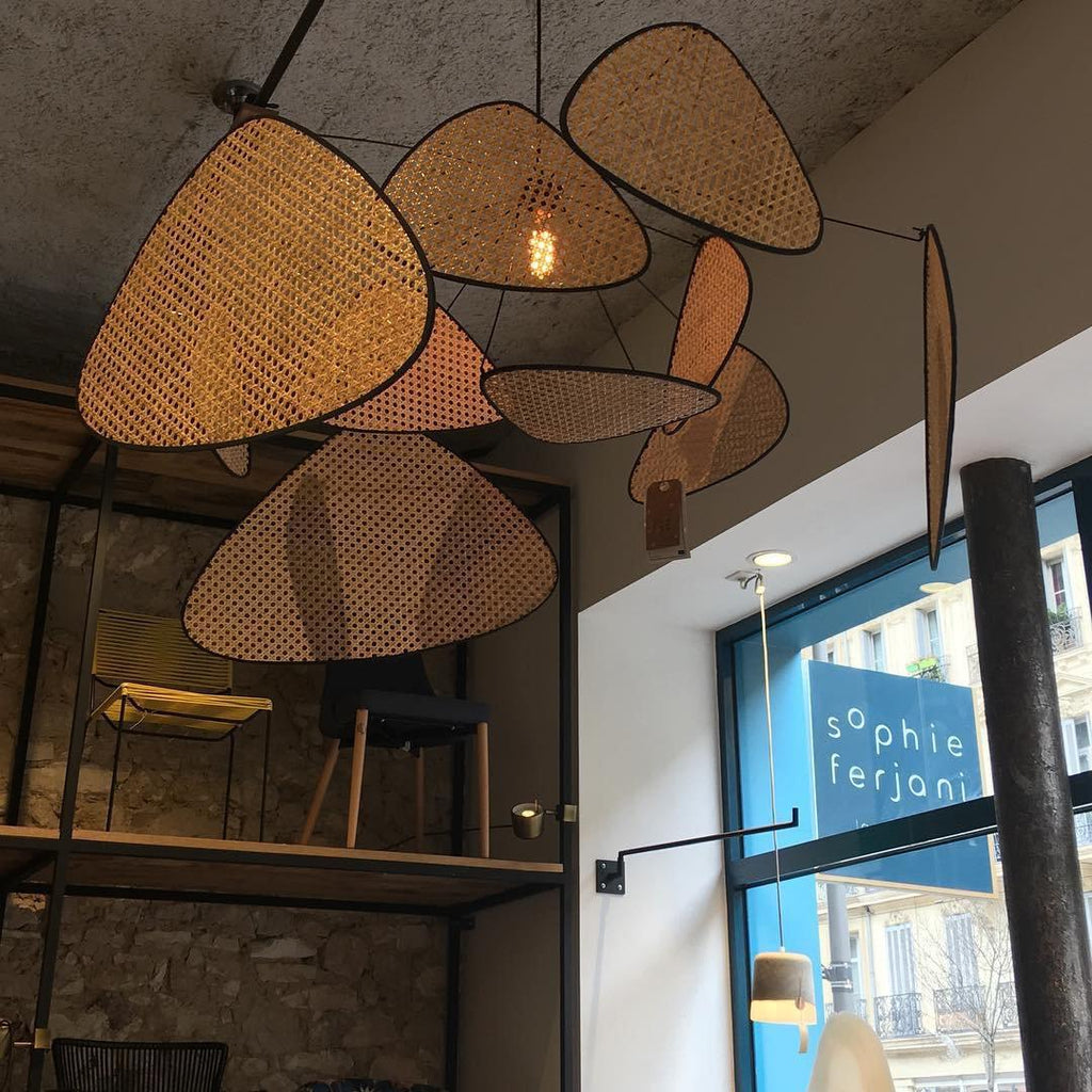 In an industrial loft with exposed stone and steel shelving, this Clérachic pendant's bamboo-weave paddles catch the daylight.
