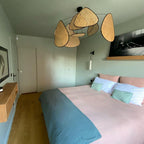 This Clérachic pendant hangs in a sage-green bedroom, its black frame and paddles above pink and teal bedding.