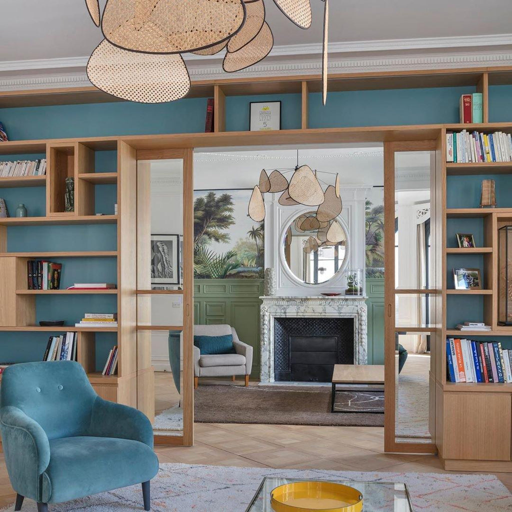 Beside a teal-painted bookshelf hallway, this Clérachic pendant hangs near a fireplace and mirror.