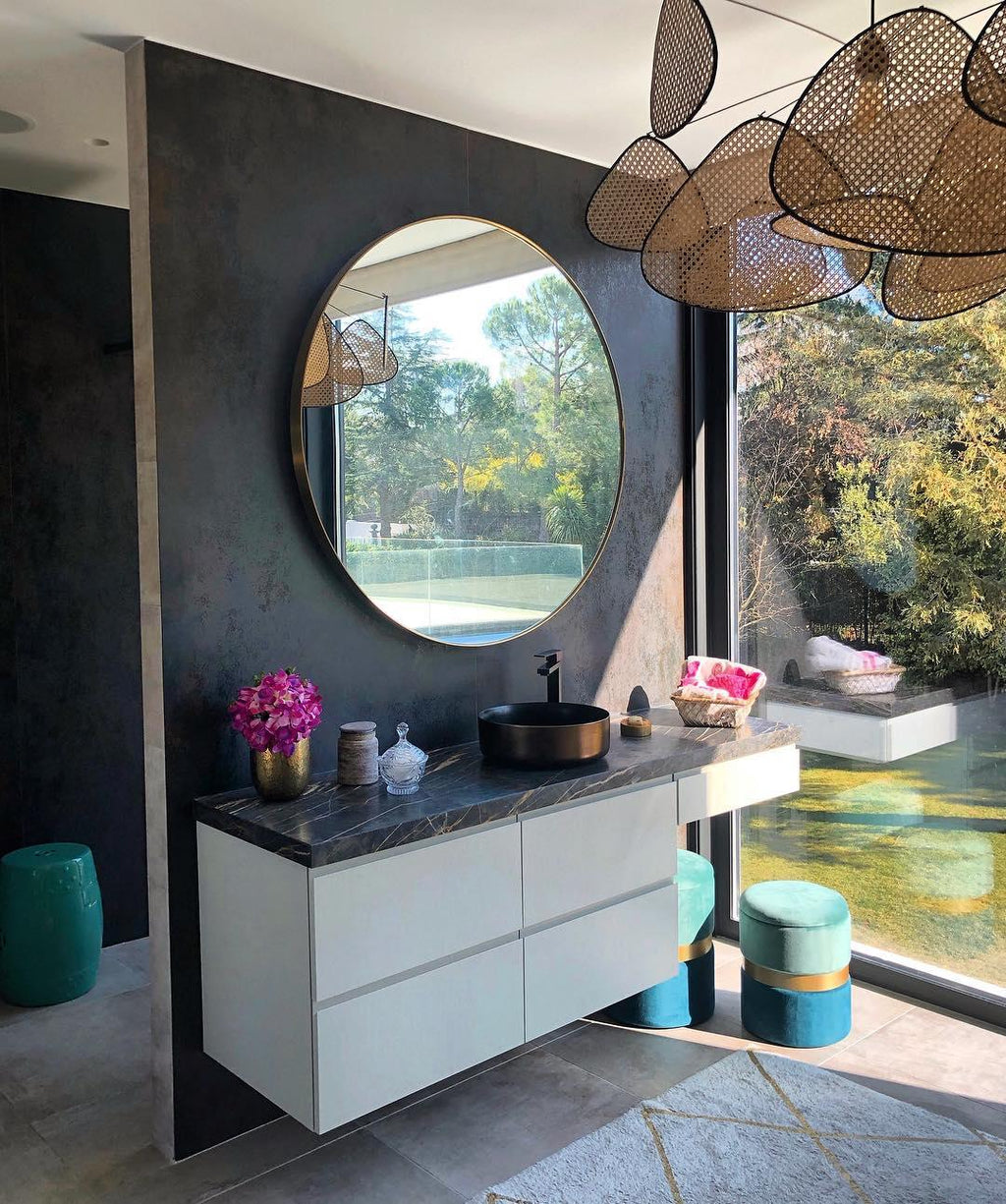 Partly visible above a bathroom with a round mirror and floating dark vanity, this Clérachic pendant catches the light.