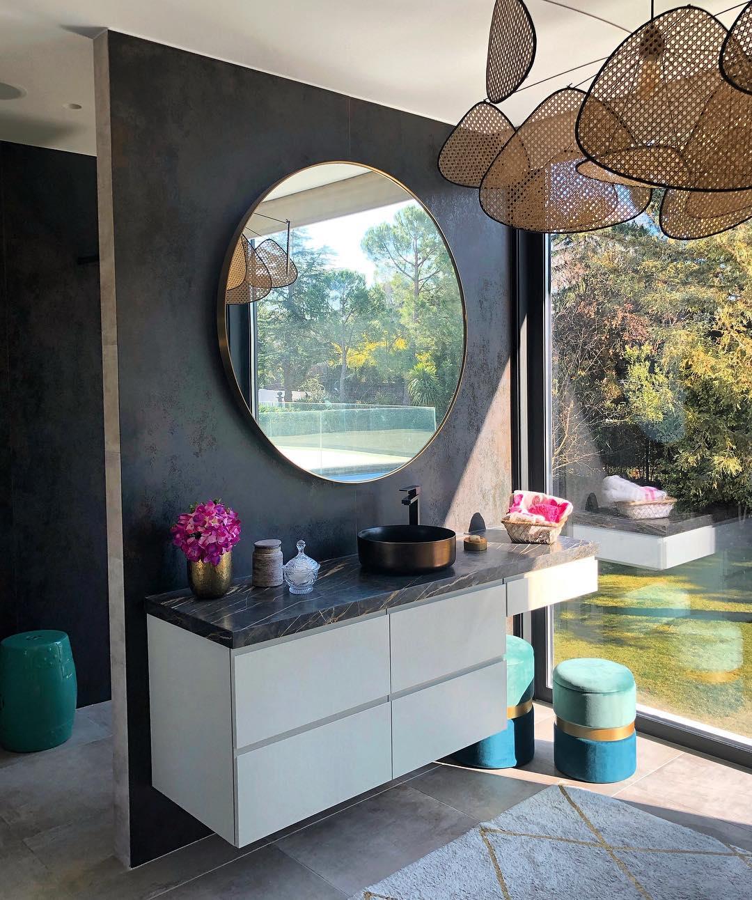 Partly visible above a bathroom with a round mirror and floating dark vanity, this Clérachic pendant catches the light.