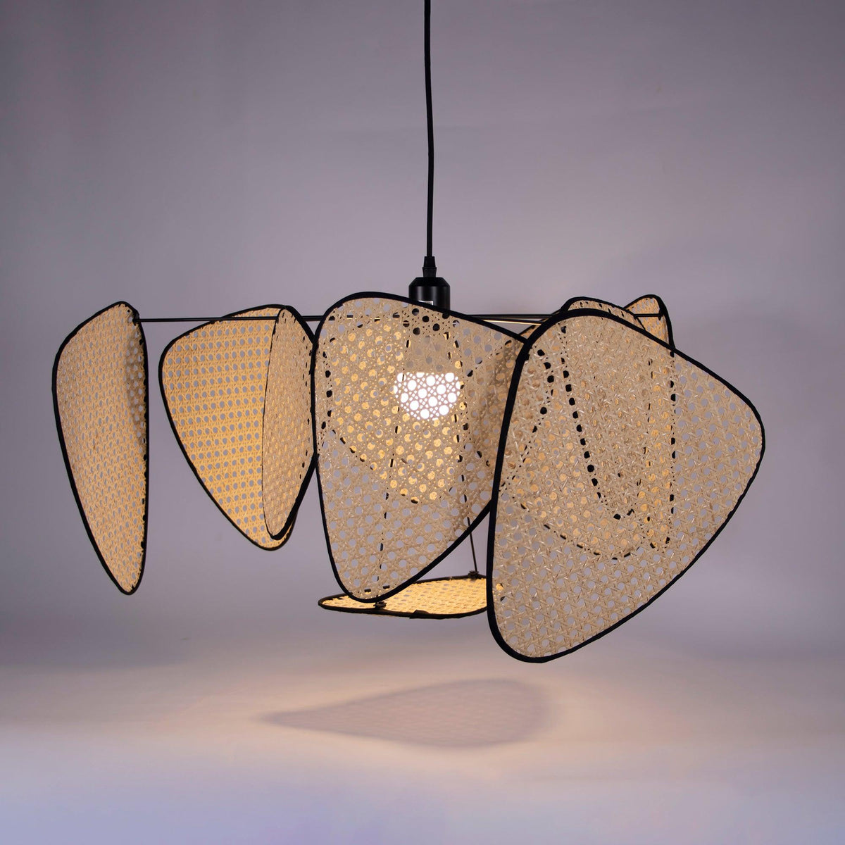 Against a lilac studio backdrop, light glows through the open bamboo weave of this Clérachic pendant's front-facing paddles.