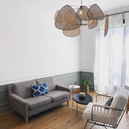 This Clérachic pendant lights a white living room furnished with a grey sofa and round coffee table by the window.