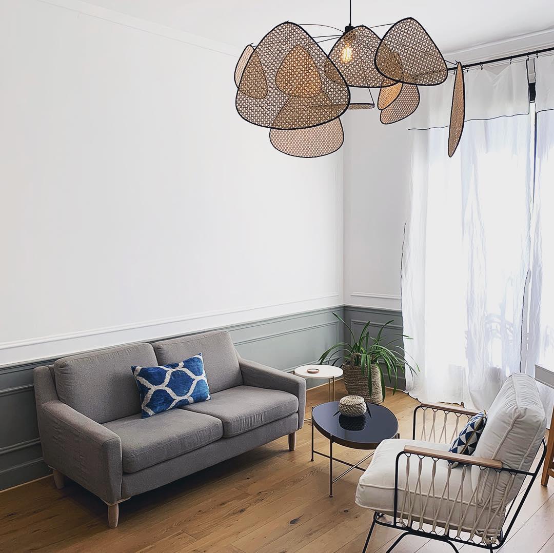 This Clérachic pendant lights a white living room furnished with a grey sofa and round coffee table by the window.