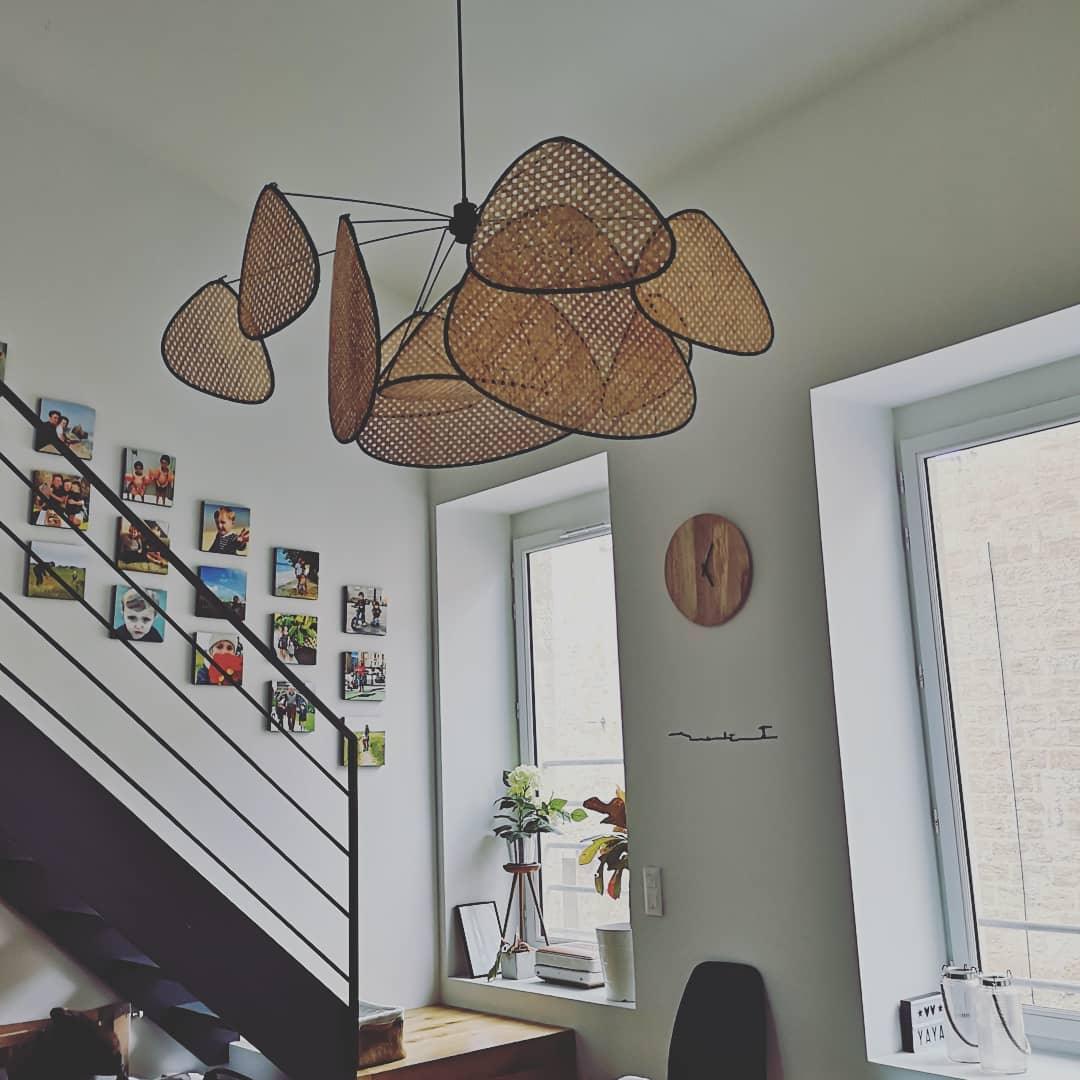 Framed photographs line the staircase wall where this Clérachic pendant hangs, against pale green paint.