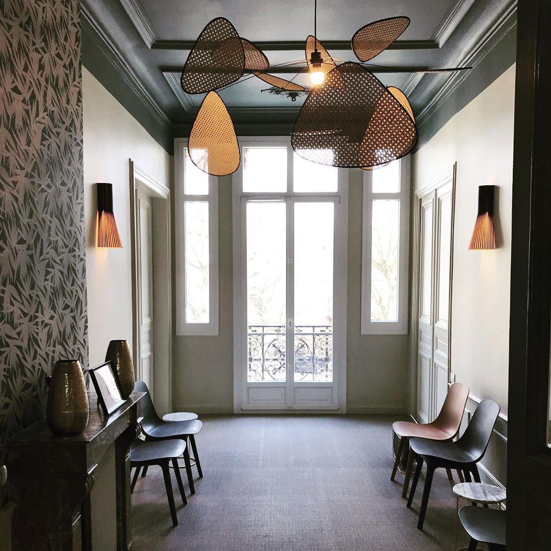 Beneath a green-painted ceiling, this Clérachic pendant hangs in a tall entry hall with French doors and wood chairs.