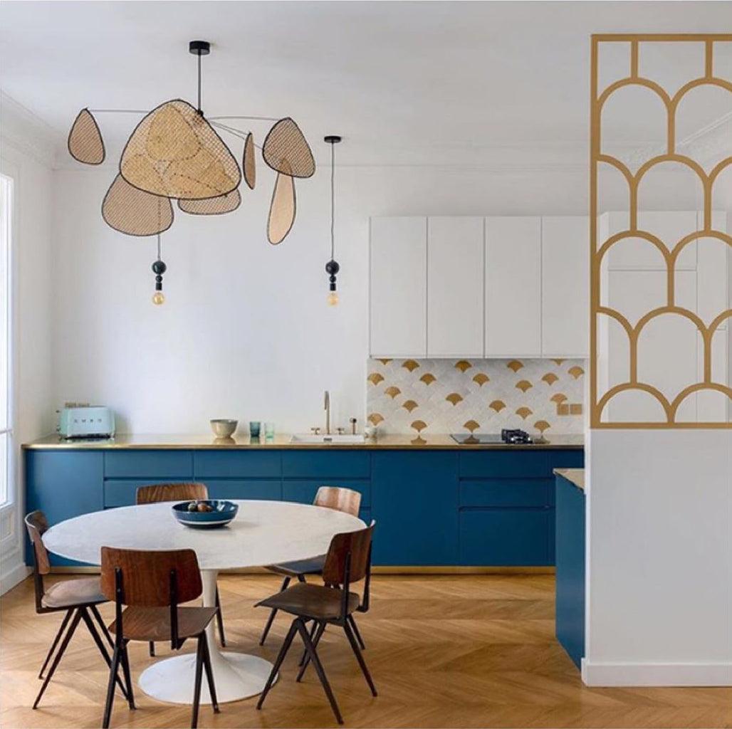 Blue cabinetry and patterned gingko tile frame the kitchen where this Clérachic pendant hangs above a round table.
