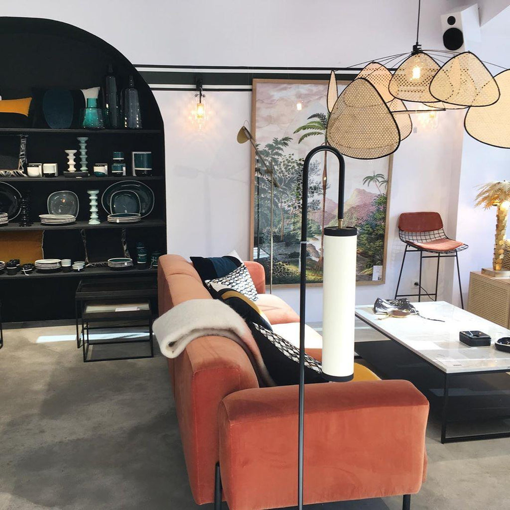 An orange velvet sofa and dark display shelving sit beneath this Clérachic pendant, with a floor lamp nearby.