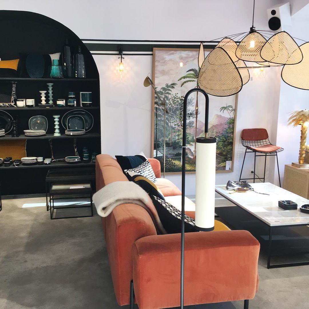 An orange velvet sofa and dark display shelving sit beneath this Clérachic pendant, with a floor lamp nearby.