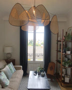 A grey sofa and coffee table sit beneath this Clérachic pendant in a living room with tall curtained windows.