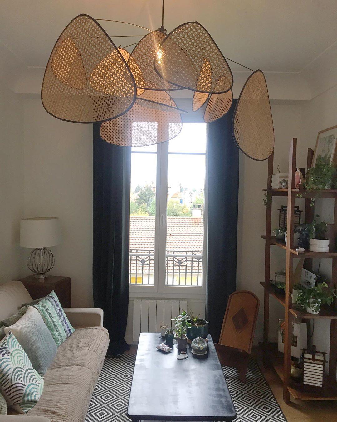 A grey sofa and coffee table sit beneath this Clérachic pendant in a living room with tall curtained windows.
