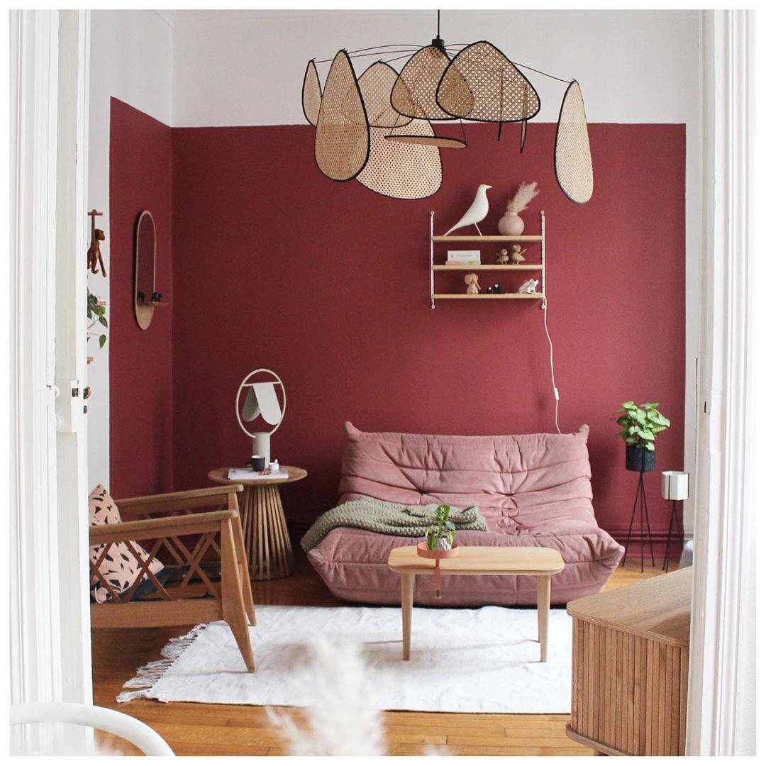 Deep red walls and a pink sofa furnish the room where this Clérachic pendant hangs beside a small curio shelf.