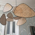 A close view of this Clérachic pendant's bamboo-weave paddles sits against an art-deco patterned wallpaper wall.