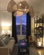 At dusk, this Clérachic pendant hangs above a blue sofa with city lights visible through the window behind.