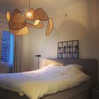 This Clérachic pendant hangs over a bed dressed in white linen, its black frame paddles beside a floor lamp.