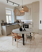 This Clérachic pendant hangs over a round marble dining table with mismatched chairs in an open kitchen.