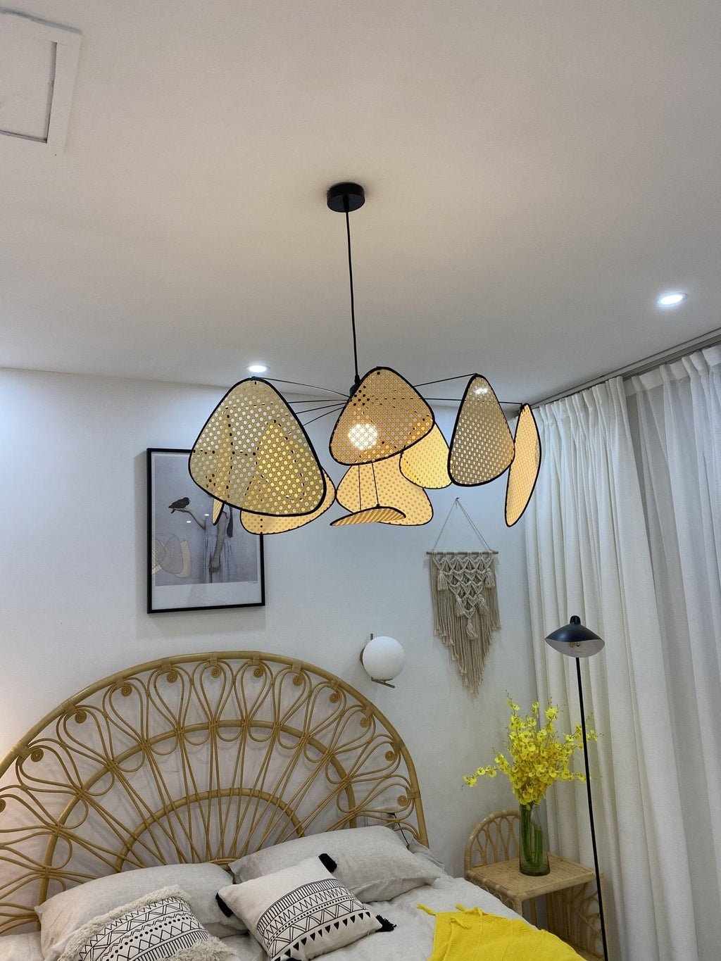 A round rattan headboard and yellow flowers furnish the bedroom where this Clérachic pendant hangs.