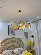 A round rattan headboard and yellow flowers furnish the bedroom where this Clérachic pendant hangs.