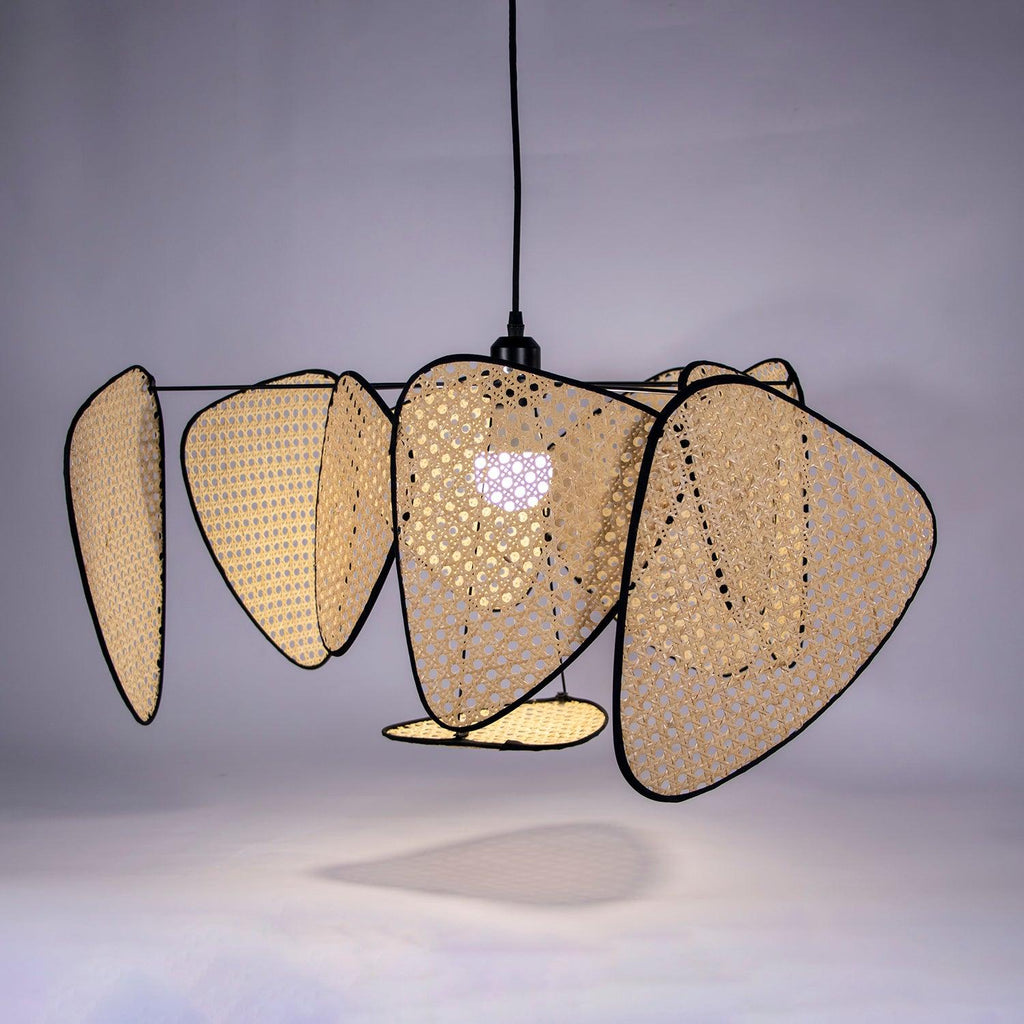 This Clérachic pendant is lit against a dark purple studio backdrop, the bulb glowing through its bamboo-weave centre panel.
