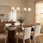 Above a wood dining table with boucle chairs, this Clérachic chandelier lights the room in brushed nickel.