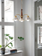 Walnut and brass chandelier with frosted shades over a dining table