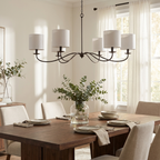 In black finish with white drum lampshades, this Clérachic chandelier hangs above a dining table by sheer curtains.