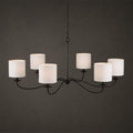 Against a dark backdrop, this Clérachic chandelier in black finish shows its six white drum lampshades.