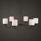 Against a dark backdrop, this Clérachic chandelier in black finish shows its six white drum lampshades.