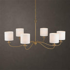 Against a dark backdrop, this Clérachic chandelier in gold finish shows its six white drum lampshades.