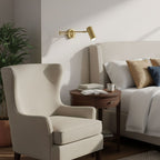 Swing arm wall sconce glowing in a softly lit bedroom