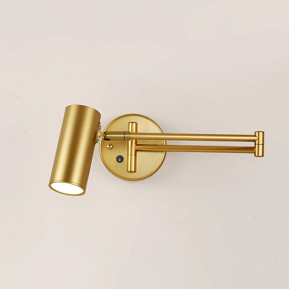 Gold swing arm wall sconce glowing softly against a wall