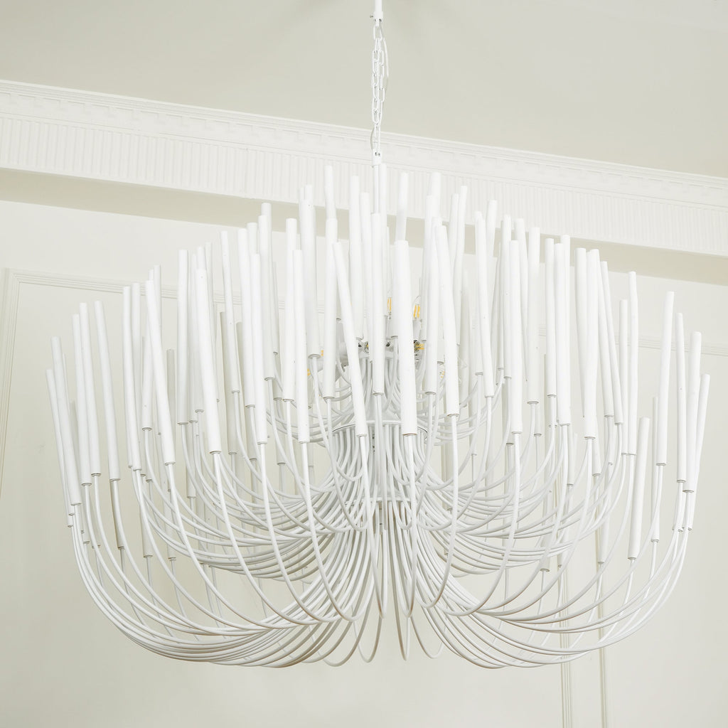 Wood rod chandelier illuminated above a long dining table