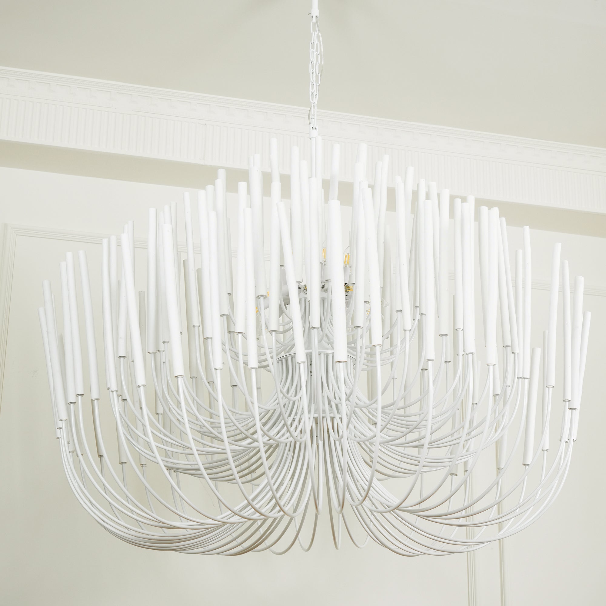 Wood rod chandelier illuminated above a long dining table