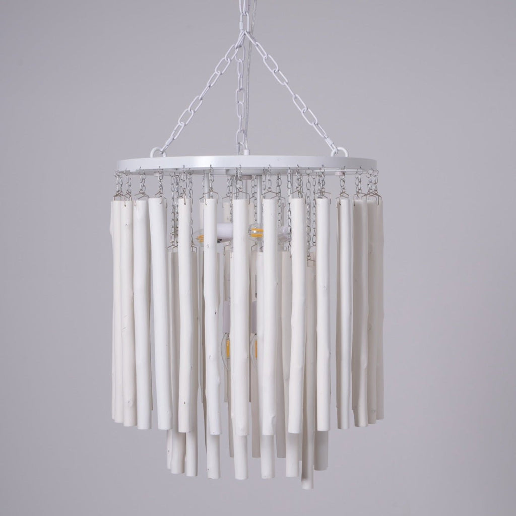 Wood rod chandelier suspended over a dining table in a bright room