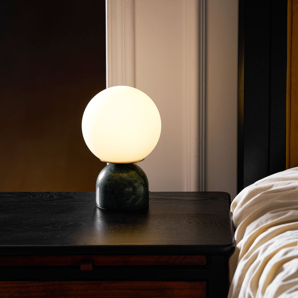 Marble base table lamp with white glass globe on a desk