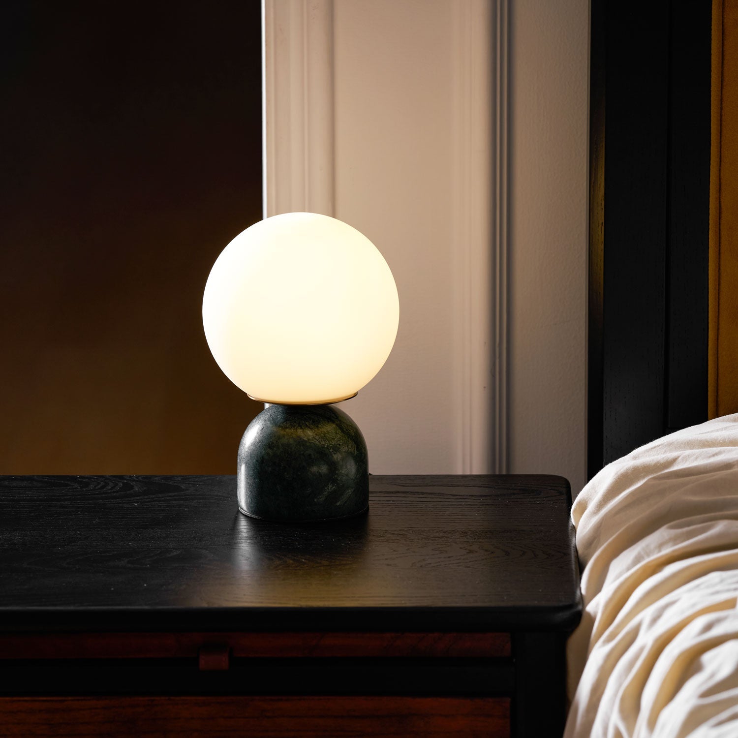 Marble base table lamp with white glass globe on a desk
