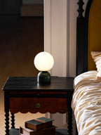 Marble table lamp with white glass orb in a styled setting