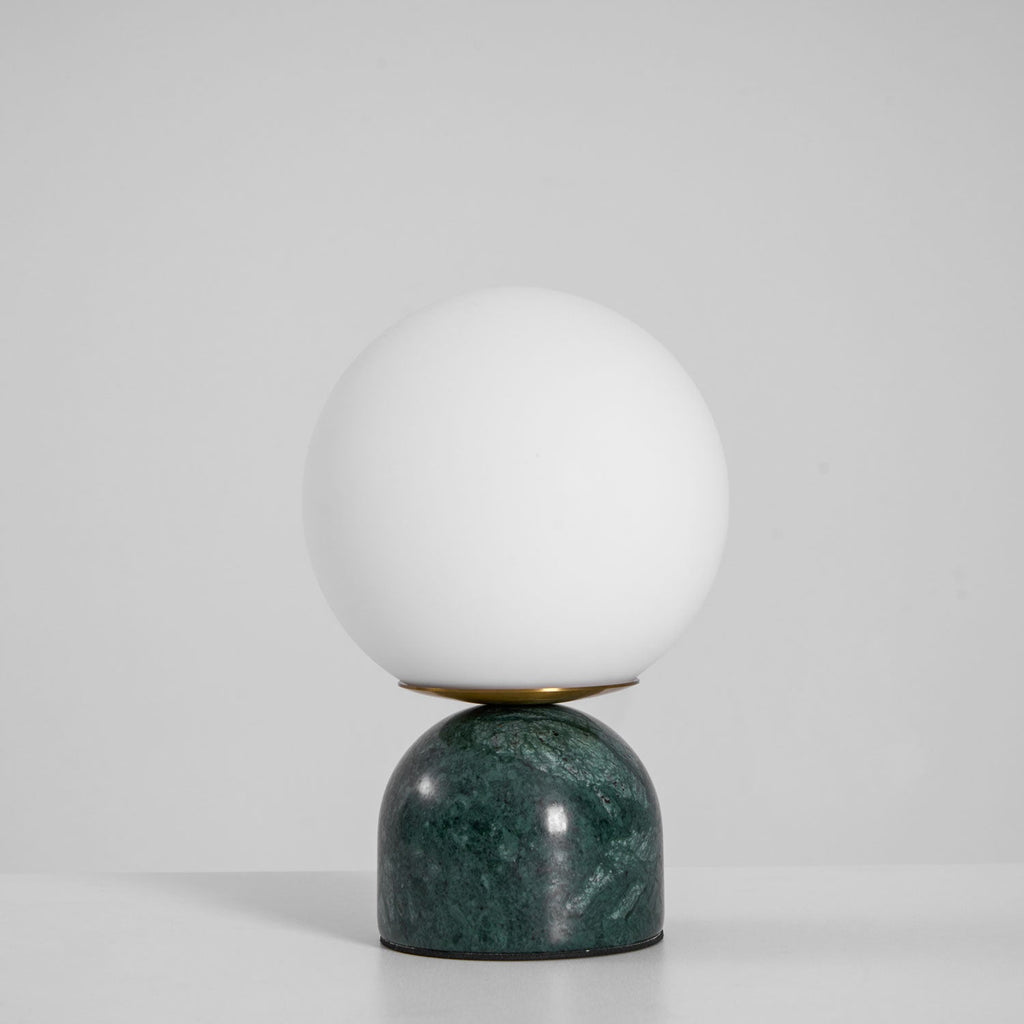 White glass globe lamp with marble base casting warm light