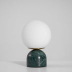 White glass globe lamp with marble base casting warm light