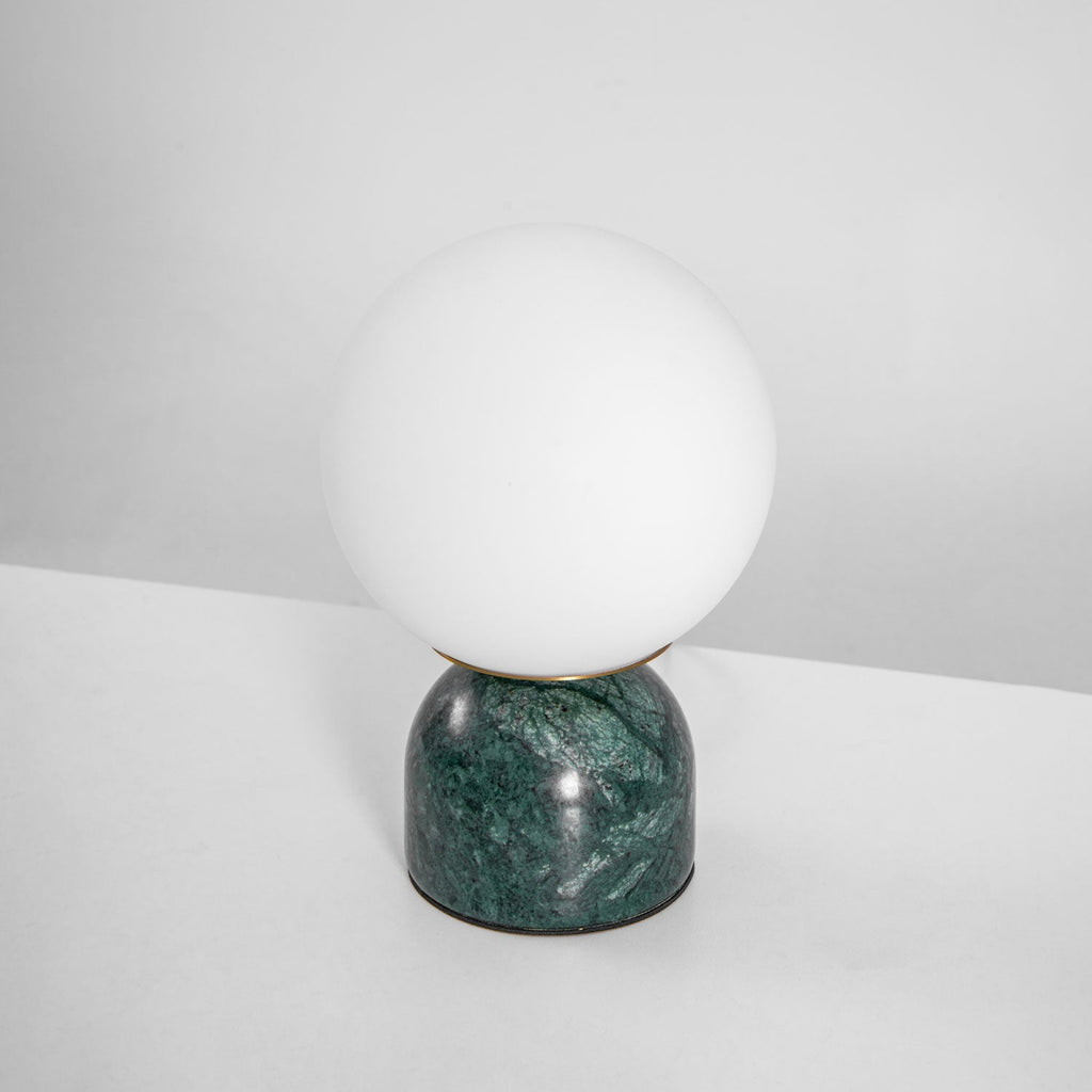Marble base table lamp with white glass orb on a desk