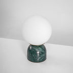 Marble base table lamp with white glass orb on a desk