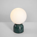 Glass orb lamp glowing warmly on a green marble base