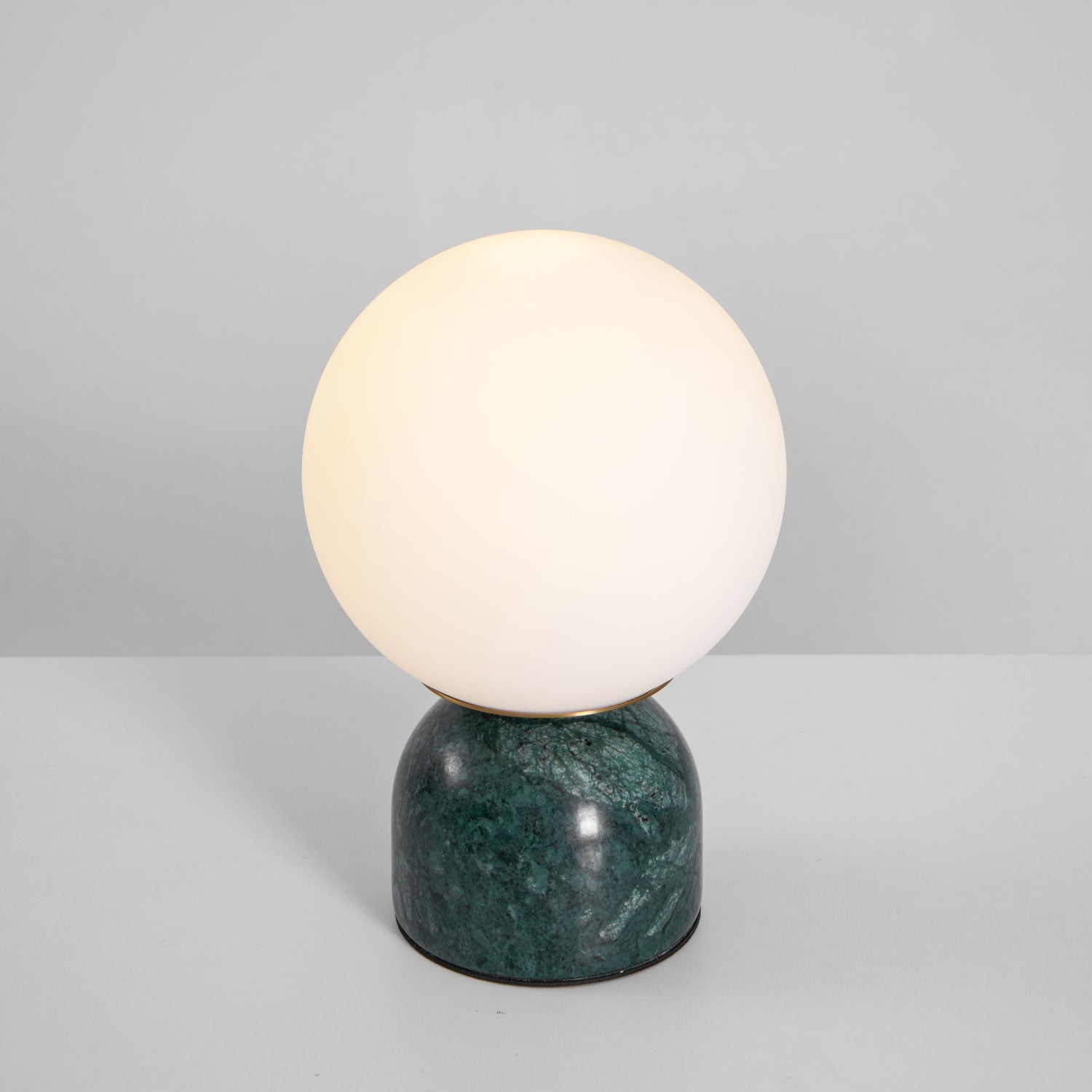 Glass orb lamp glowing warmly on a green marble base