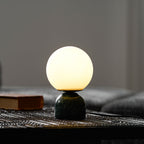 White glass orb table lamp on a white marble base