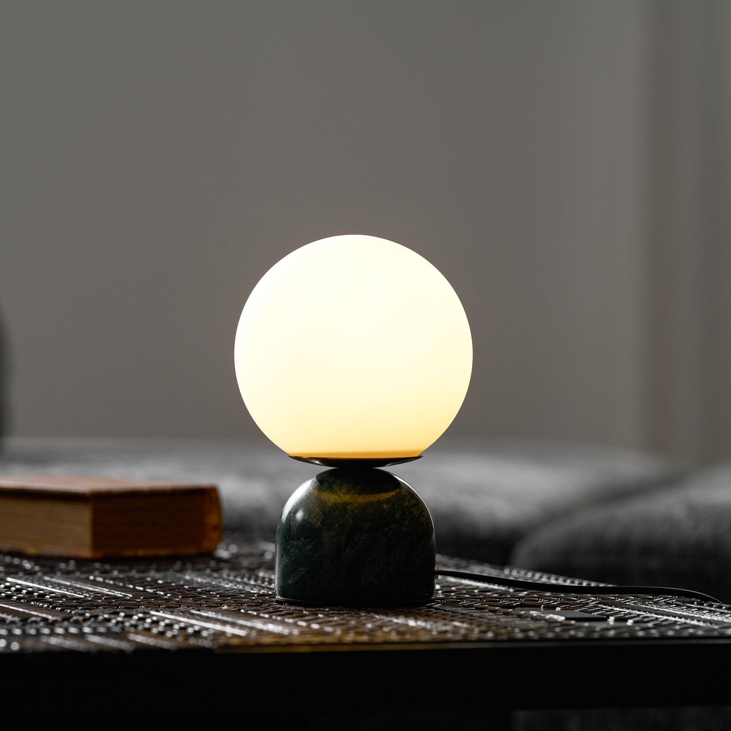 White glass orb table lamp on a white marble base