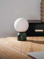 Sylas lamp with glowing glass globe on a side table
