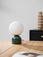Glass orb table lamp casting a warm glow on a shelf